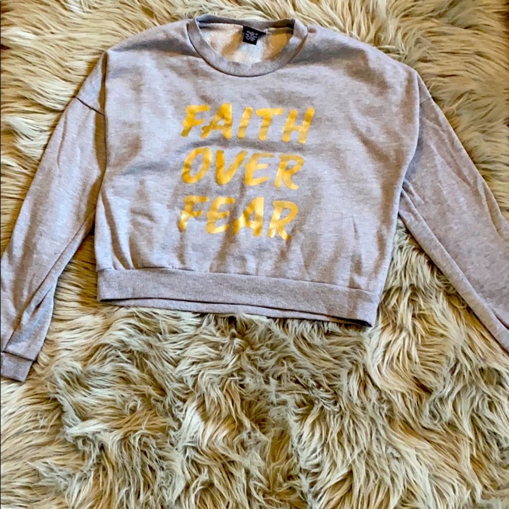 A cropped sweatshirt with gold words written on it